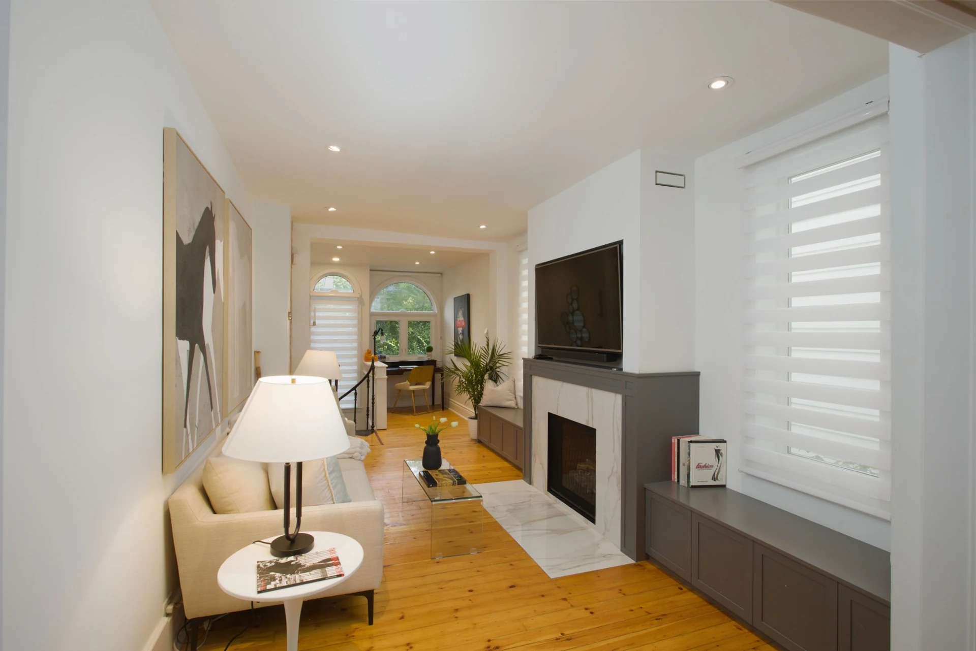 Carefully lit Toronto living room with a fireplace, warm timber floors and layered furnishings