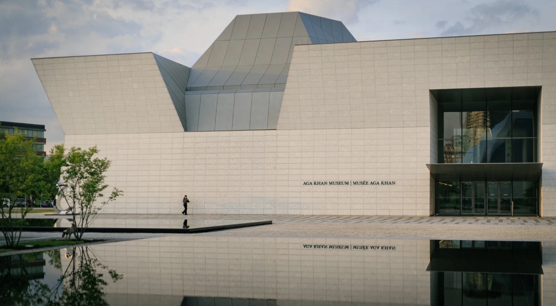 Geometric limestone forms of the Aga Khan Museum reflected in water